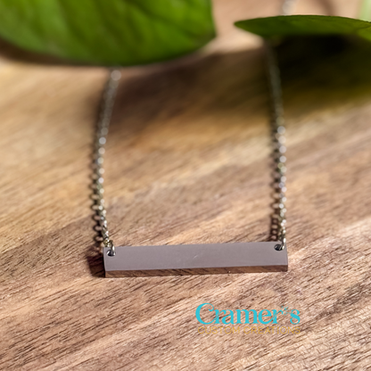 a silver horizontal bar necklace on a wood background