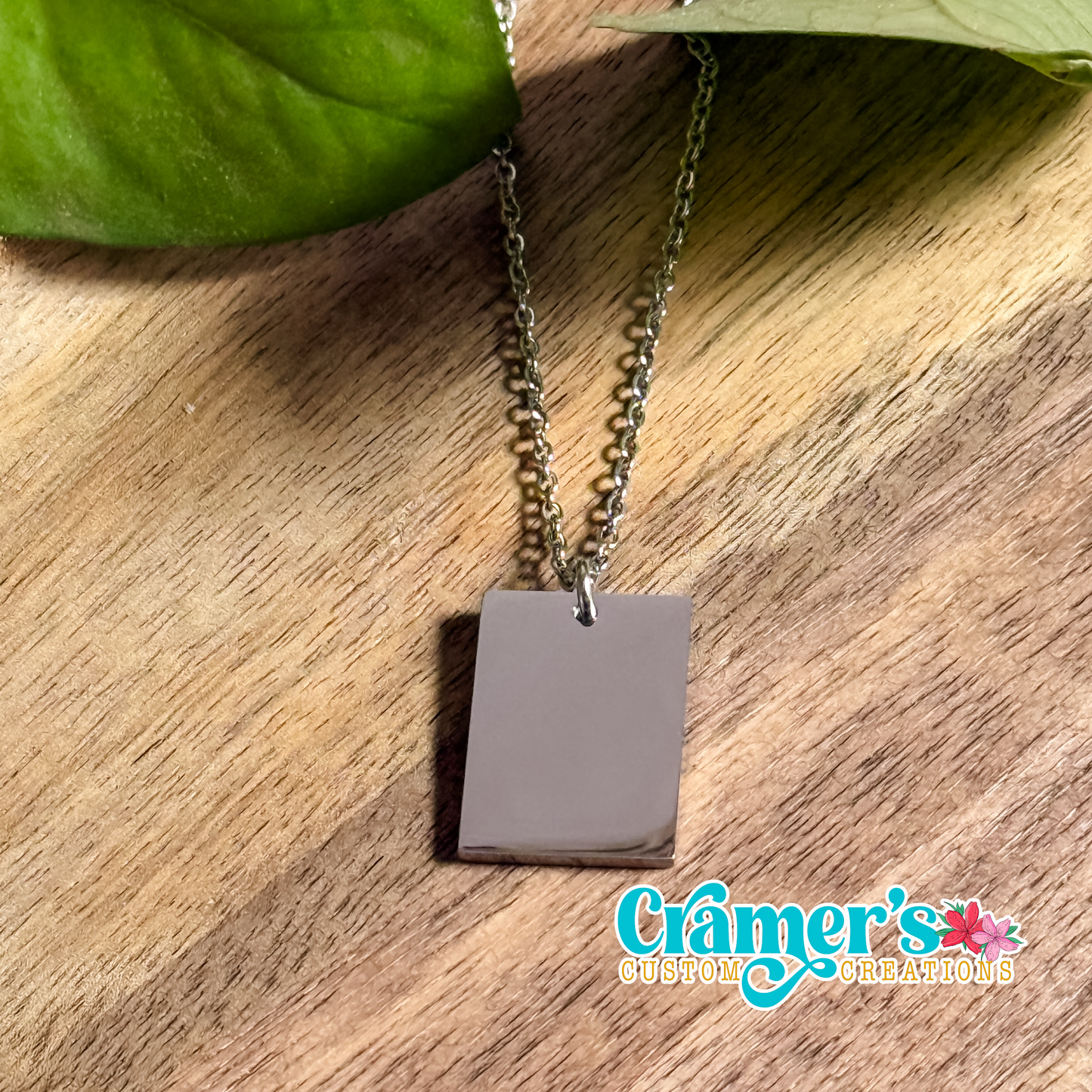 a silver rectangle necklace on a wood background