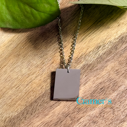 a silver rectangle necklace on a wood background