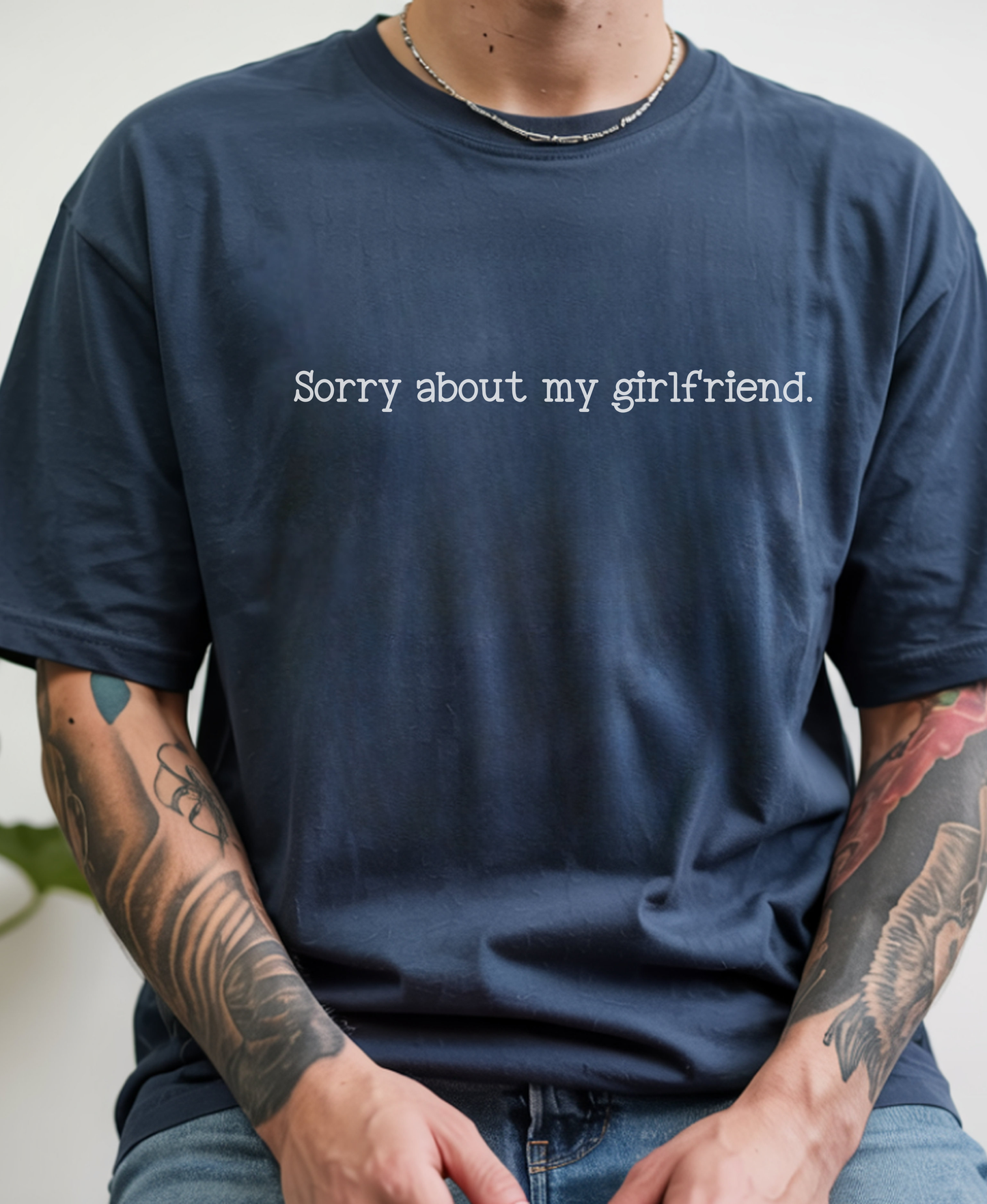 A person wearing an oversized navy blue t-shirt with the text 'Sorry about my girlfriend.' printed in white across the chest.