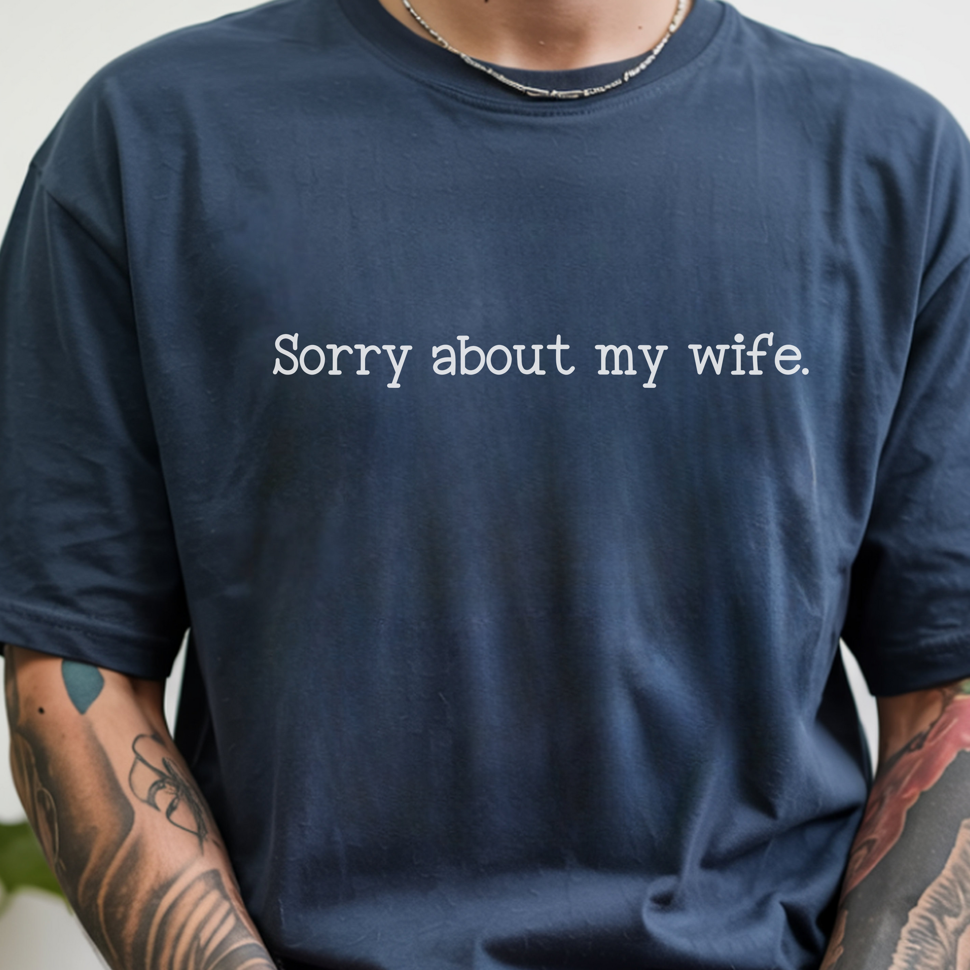 A person wearing an oversized navy blue t-shirt with the text 'Sorry about my girlfriend.' printed in white across the chest.