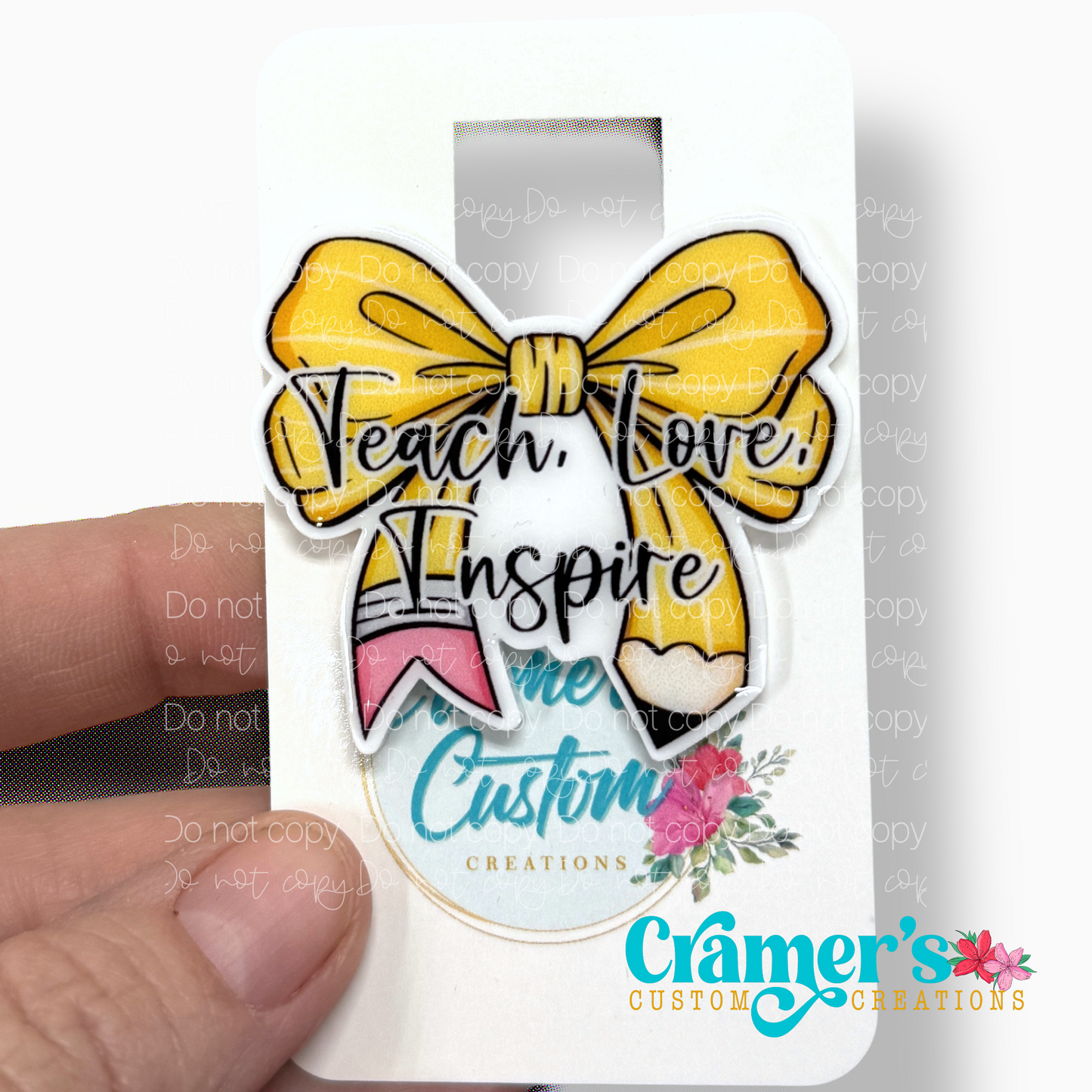  showing a non glitter option of a face plate for a badge with the words teach love inspire on a bow colored like a pencil