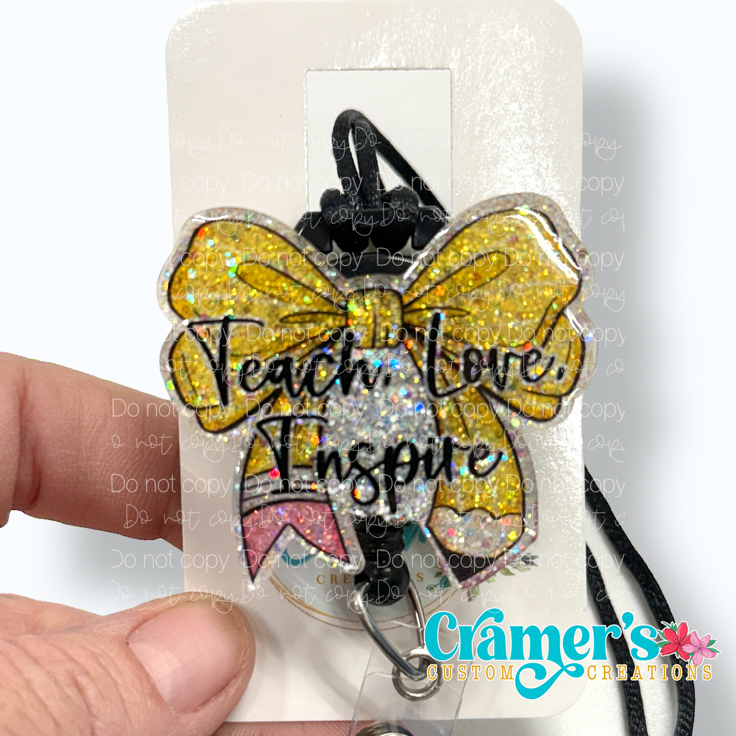 badge reel showing a glitter option of a badge with the words teach love inspire on a bow colored like a pencil