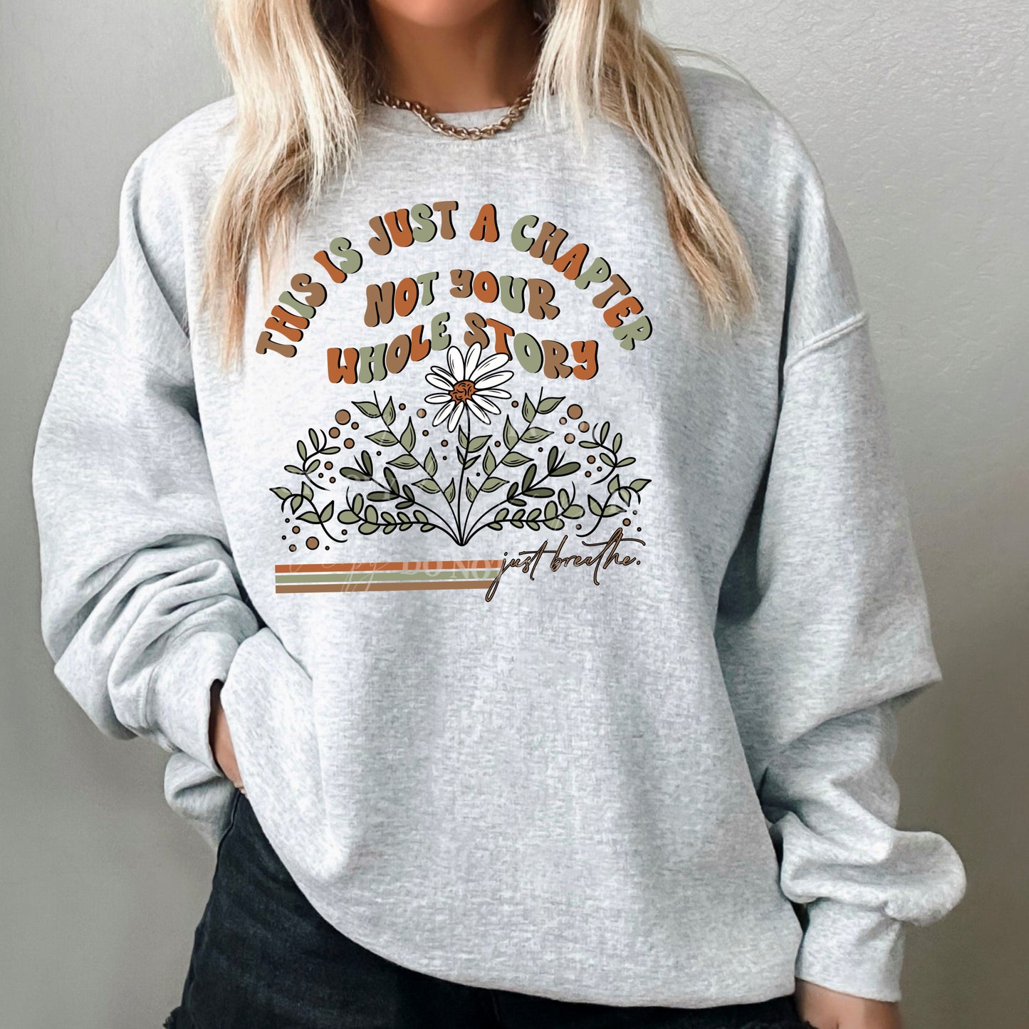 woman wearing a light grey sweatshirt that says this is just a chapter not your whole story