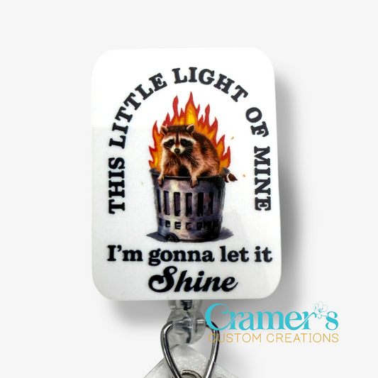 Sticker with a raccoon in a trash can and text 'This little light of mine I'm gonna let it shine' on a white background.