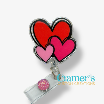 Retractable badge holder with heart designs and a glittery accent, branded 'Cramer's Custom Creations'.