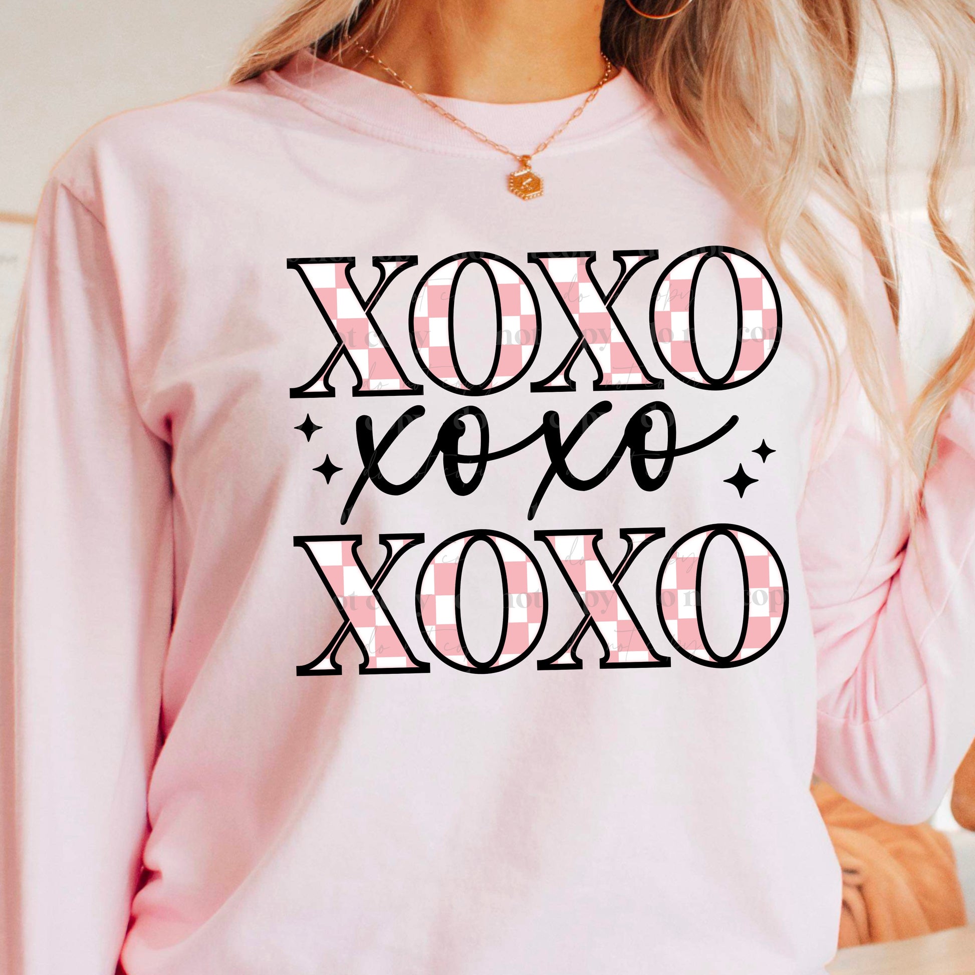 girl wearing a pink sweatshirt that has xoxo across it three times with pink check in the letters