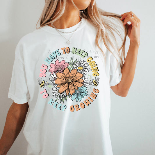 A person wearing a white t-shirt with a colorful floral design and the text 'You have to keep going...' printed on the front.