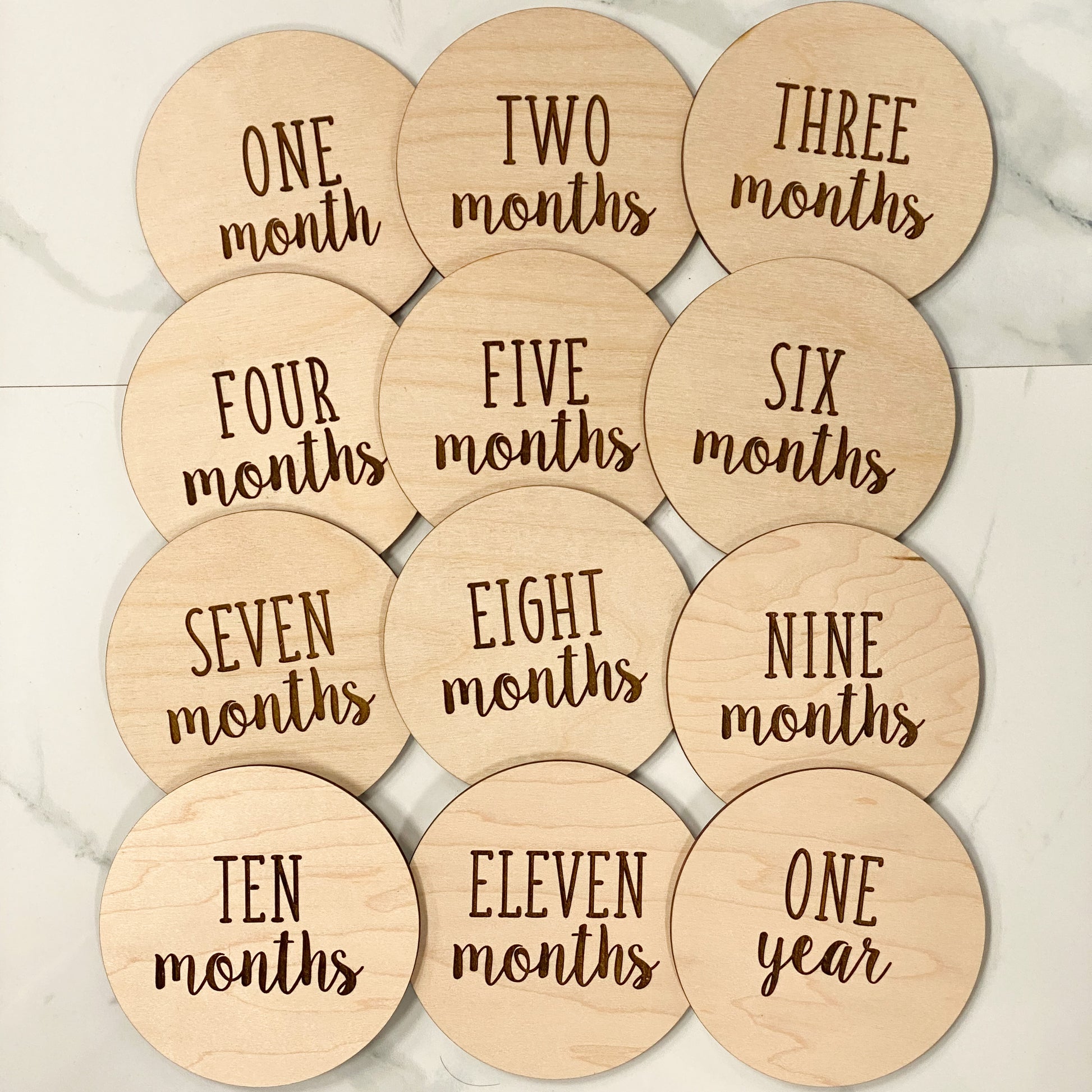 wood discs engraved with one month thru one year on a white background