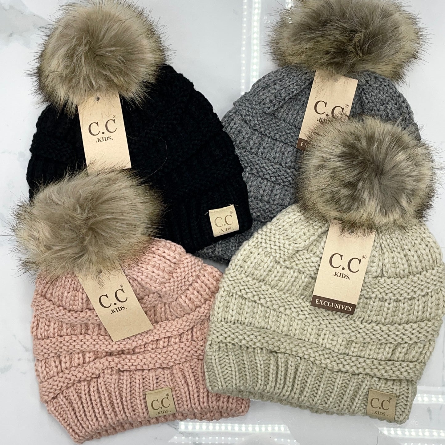 4 kids pom pom hats in multiple colors on a white backround