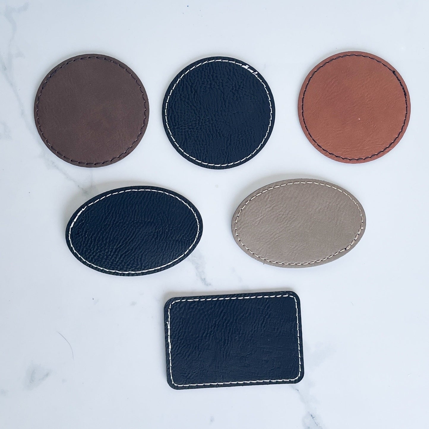multiple sizes and colors of leather patches on a white background