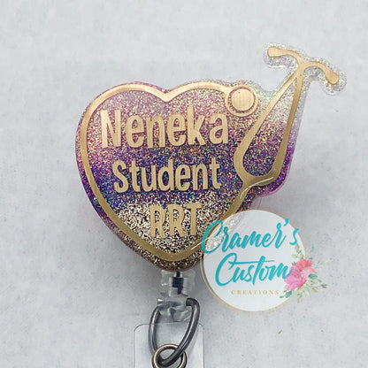 a stethoscope heart badge reel with gold writing and a hold stethoscope, with the glitter being a wine, pink, gold ombre, on a  white background